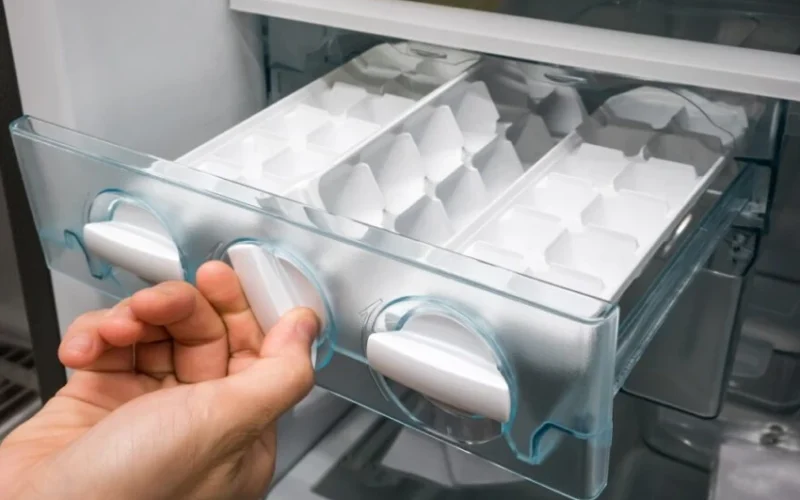 Hand taking ice from an ice maker drawer
