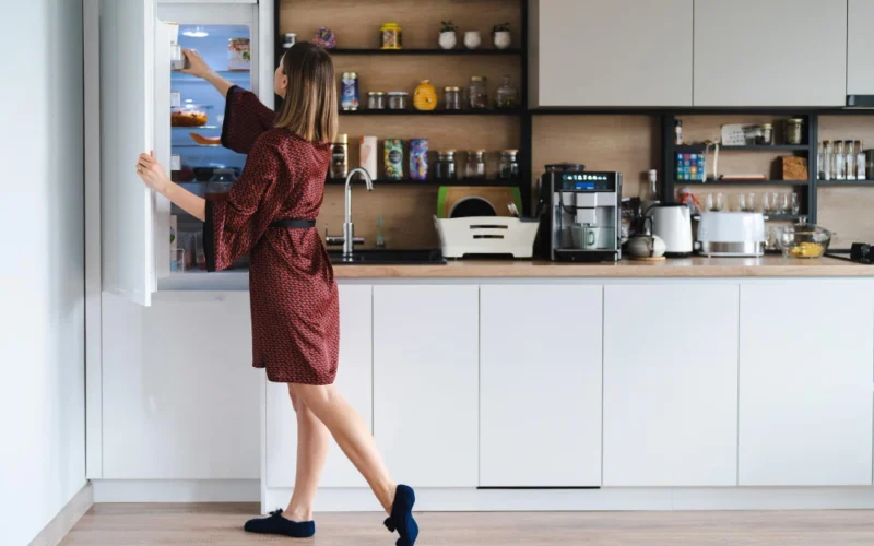 Woman at an open refrigerator in a modern kitchen